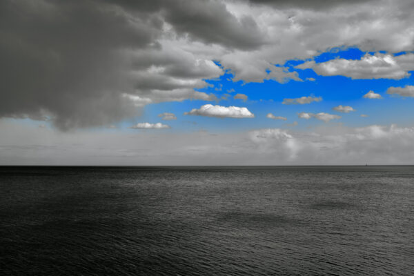 Blue sky, white fluffy clouds, dark gray clouds over menacing Lake Michigan